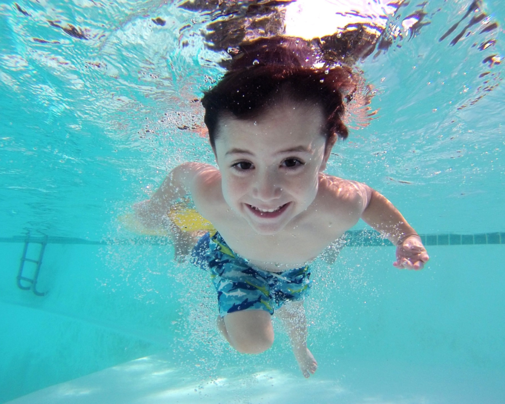 Boy swimming and smiling underwater.
