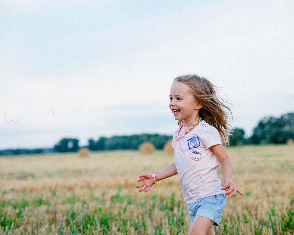 Young girl running through the tall grass.