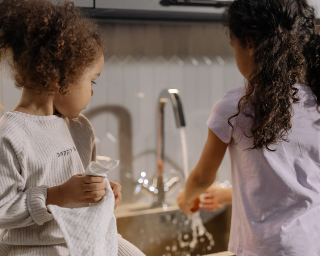 Sisters washing and drying dishes at the sink.