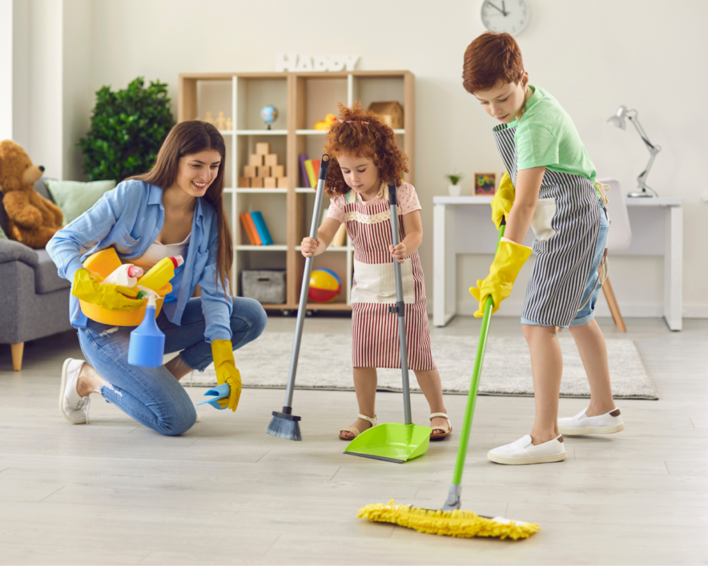 Boy and girl sweeping the floor with mother kneeling beside them.