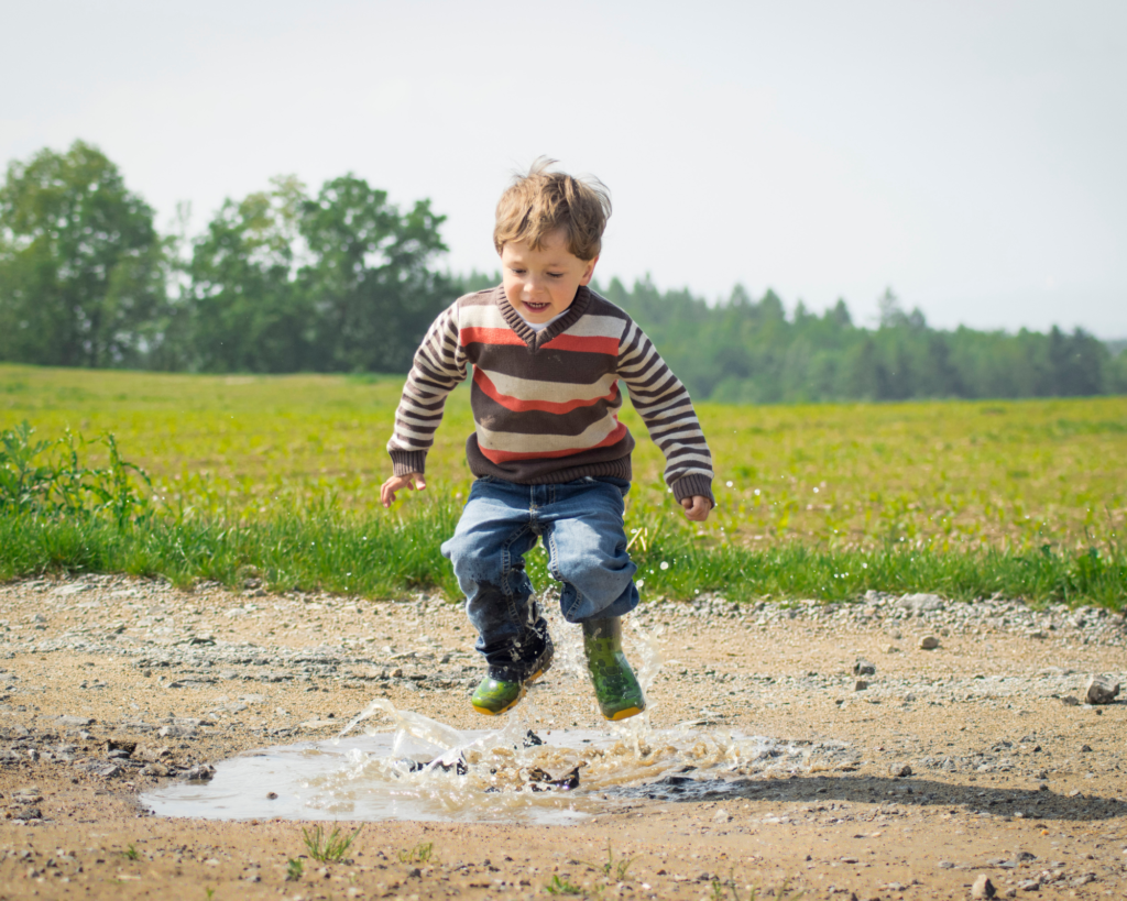 Boy jumping in a puddle.
