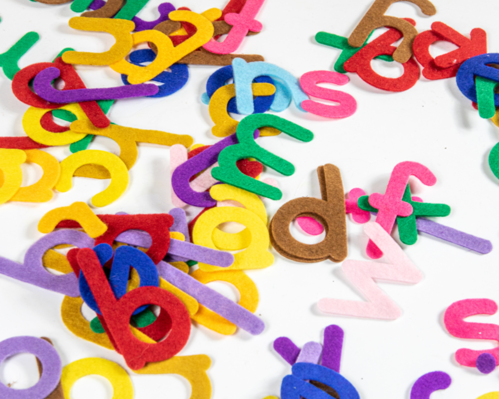 Colorful felt letters sprinkled on work space.