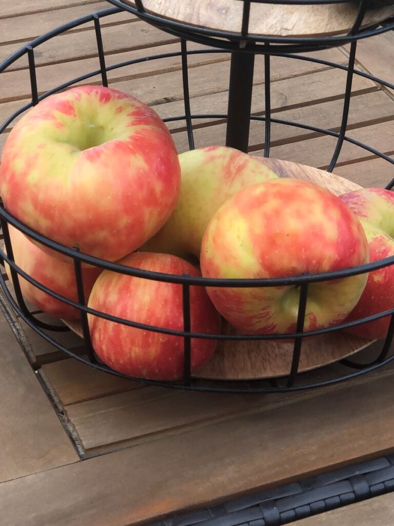 Black fruit basket with red and green honeycrisp apples.