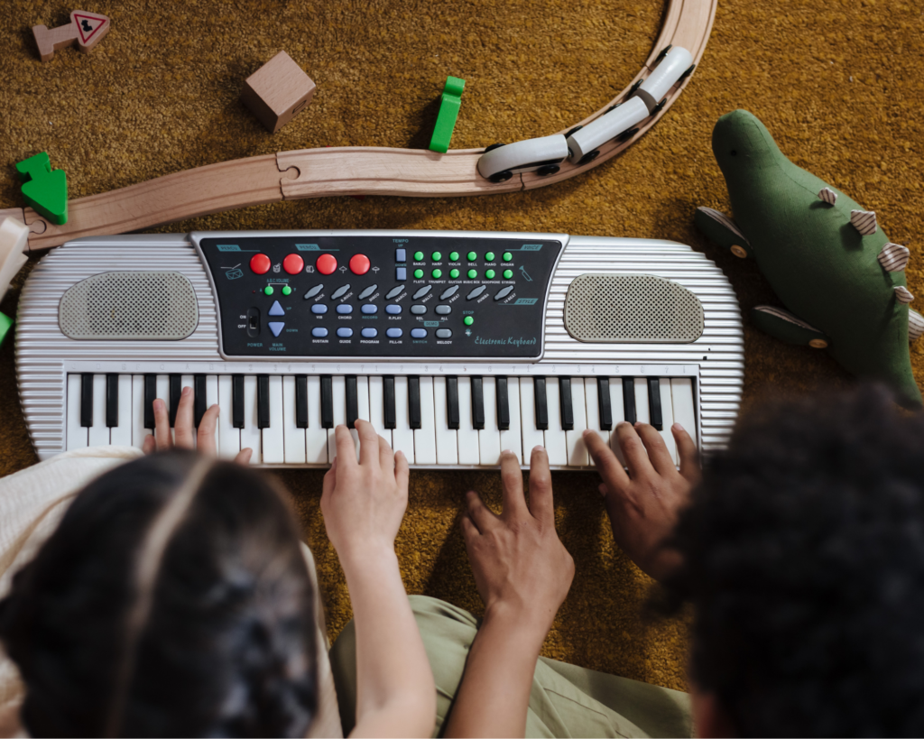 Two preschool age children pressing keys on a keyboard.